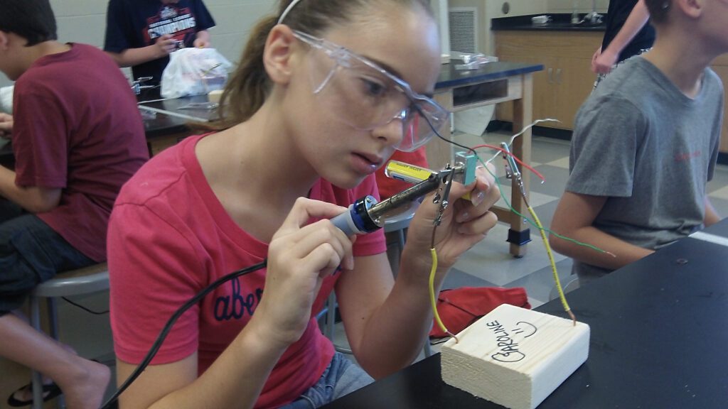 A summer camper builds a structure out of wires and wood at the Challenger Learning Center maker summer camp.