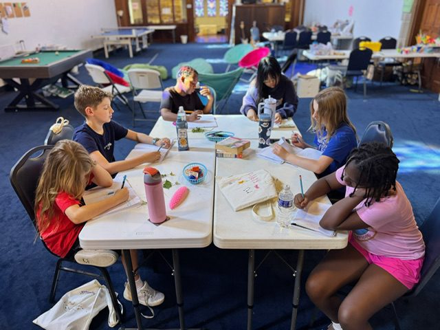 Kids write in notebooks at the Gateway Writing Project