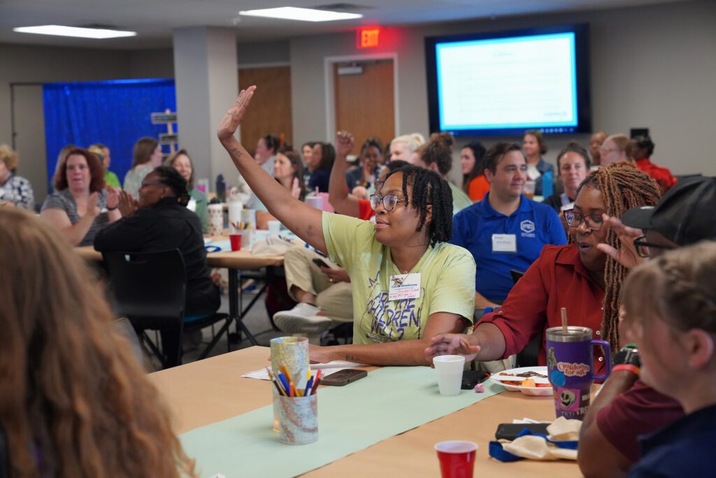 A camp provider raises their hand to participate in the 2026 camp summit opening remarks.