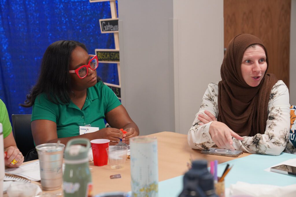 Two camp providers discuss among the table data collected during the survey of families. 