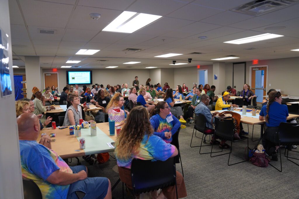 The conference room at Delmar Divine is filled with camp providers listening intently to a raffle drawing. They site at tables in groups of 6-8 and most of them are wearing tshirts with their camp logo on them.