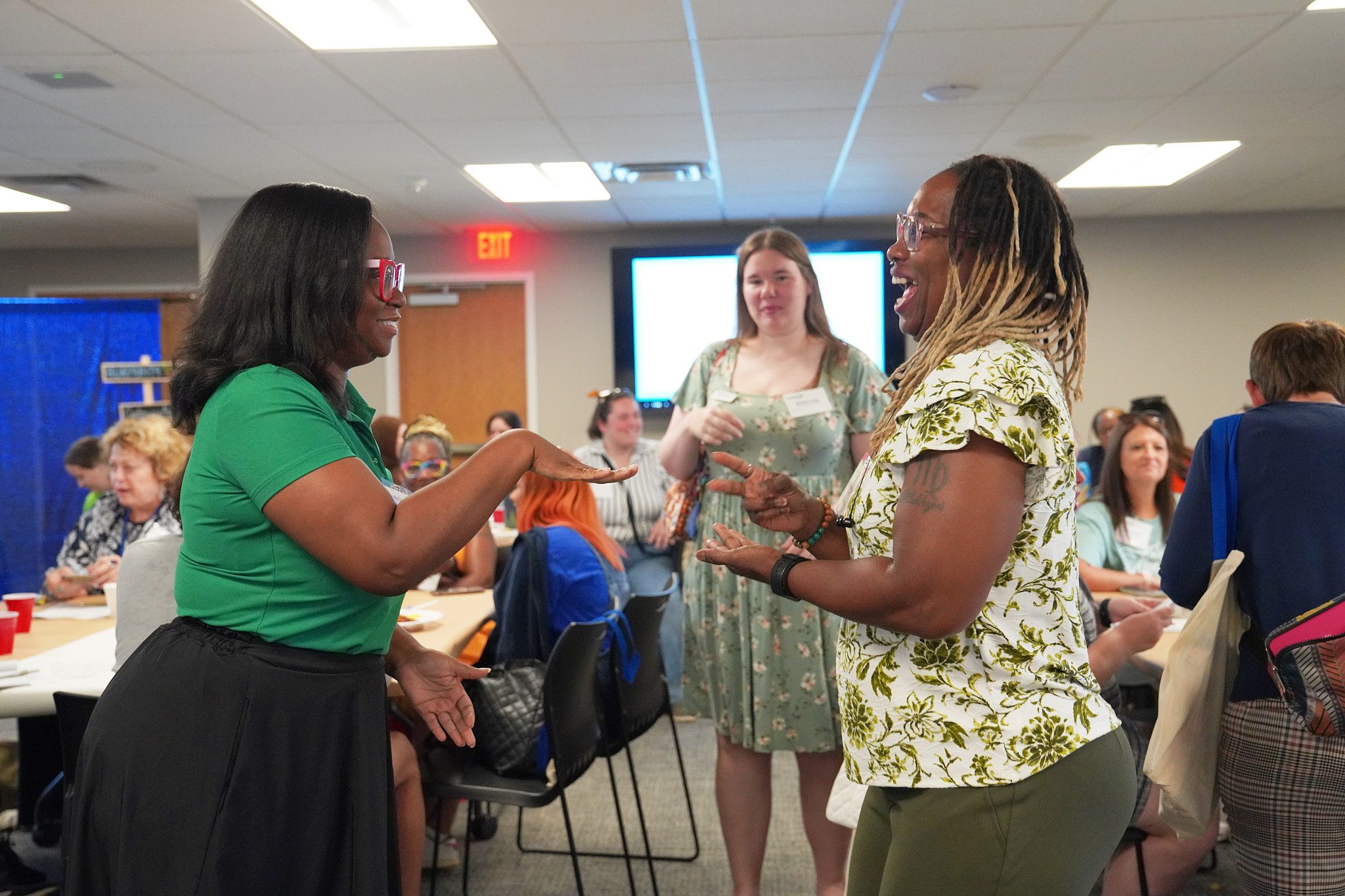 Two camp providers participate in the rock paper scissors competition. One woman has just won with scissors and she smiles as the other woman holds out. a hand for paper.