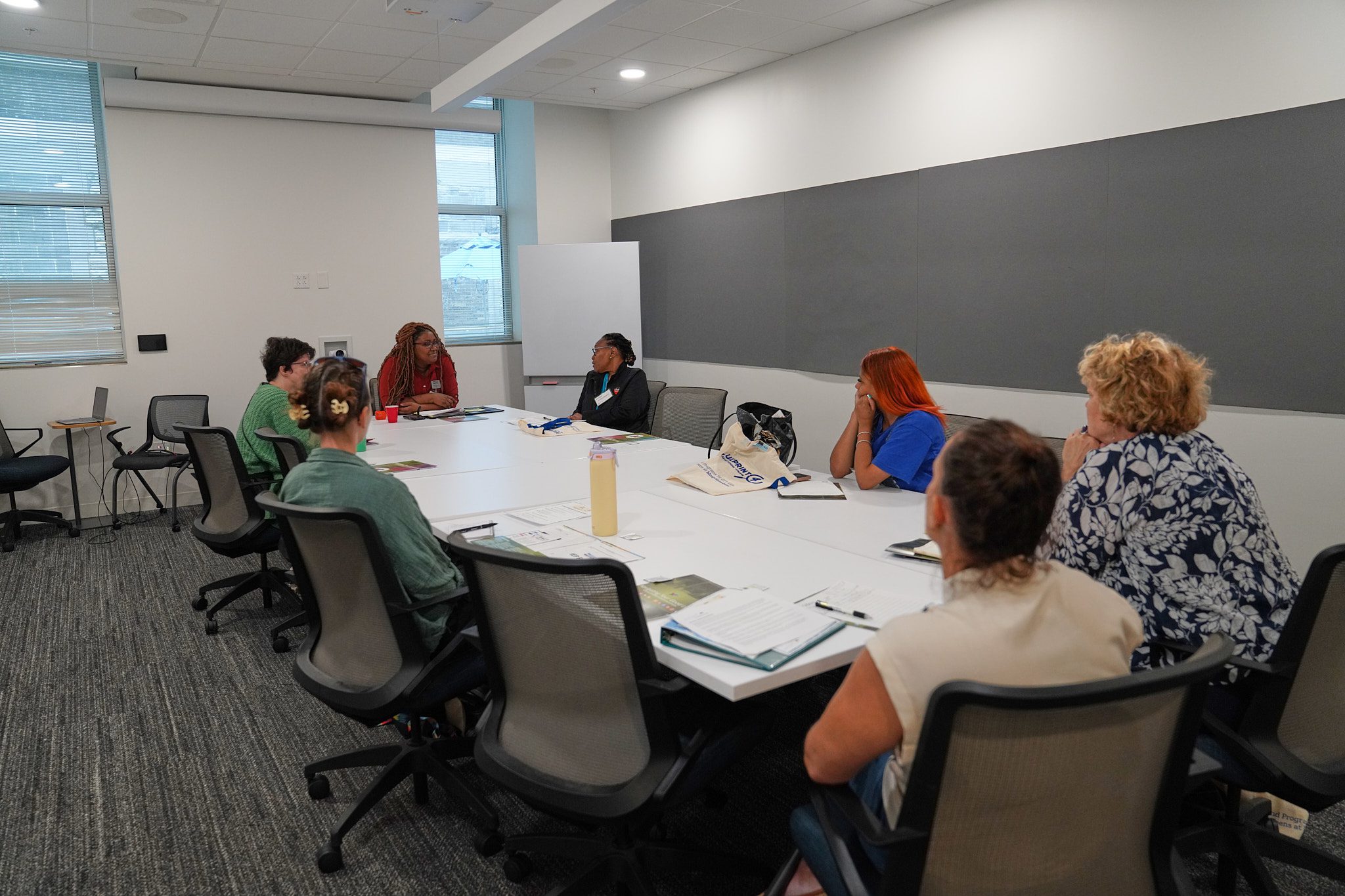 A group of camp providers sit in a conference room at a table to discuss challenges facing summer camps.